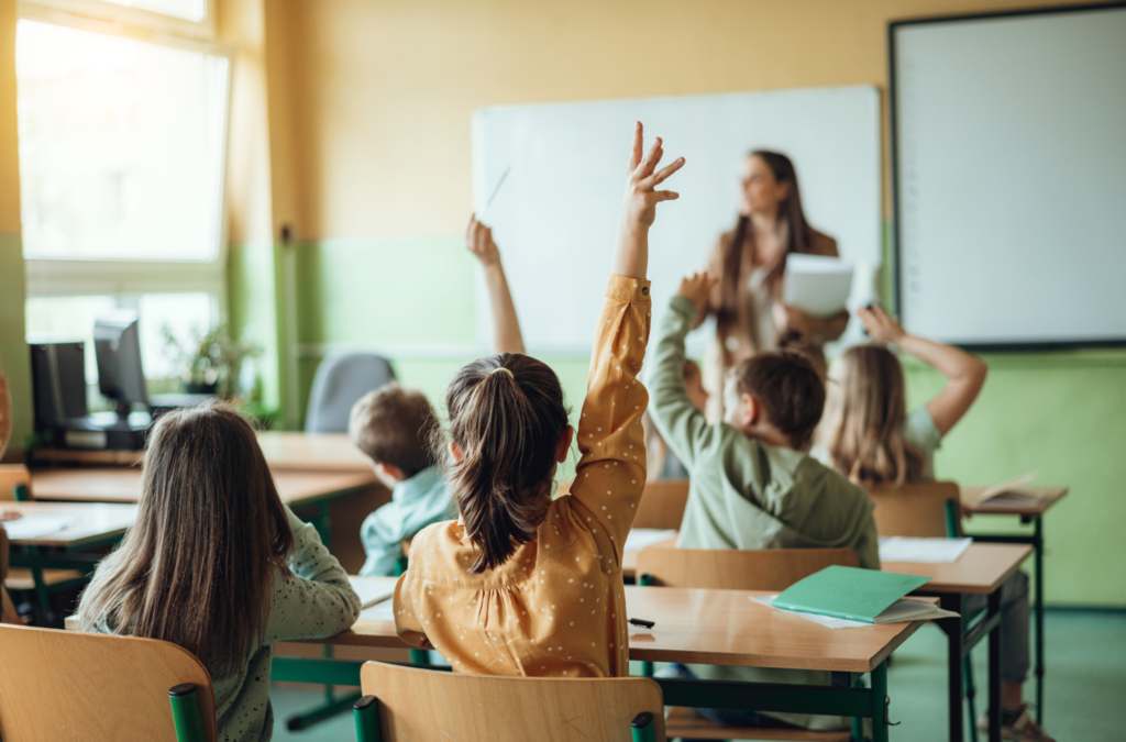 School Children raising hands for teacher