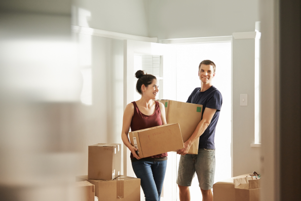 Couple moving boxes into house