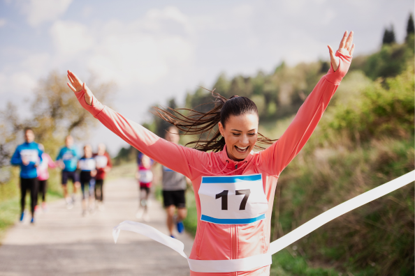 Lady crossing finish line with hands up in celebration